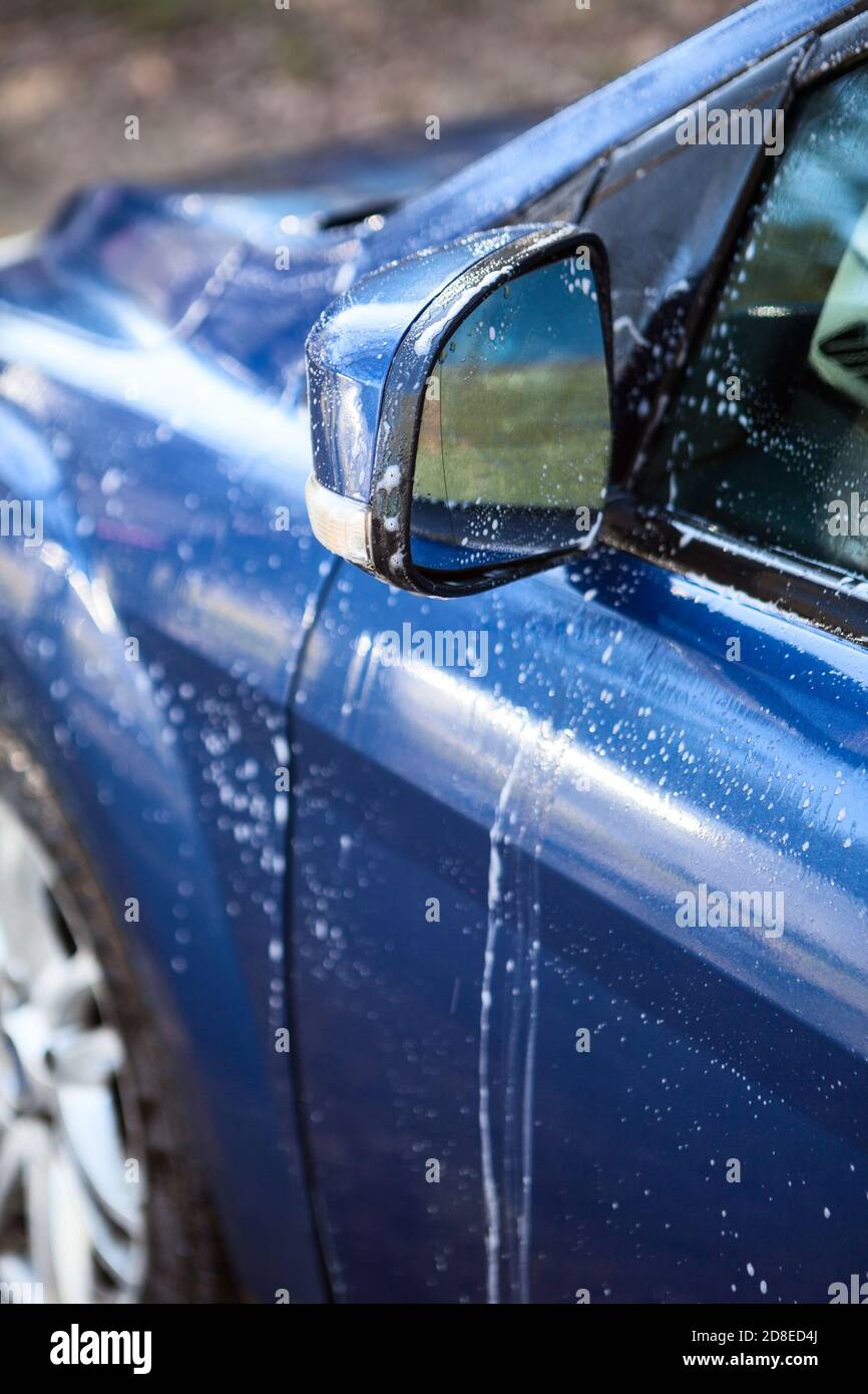Car side mirror and door with foam during car washing, closeup view