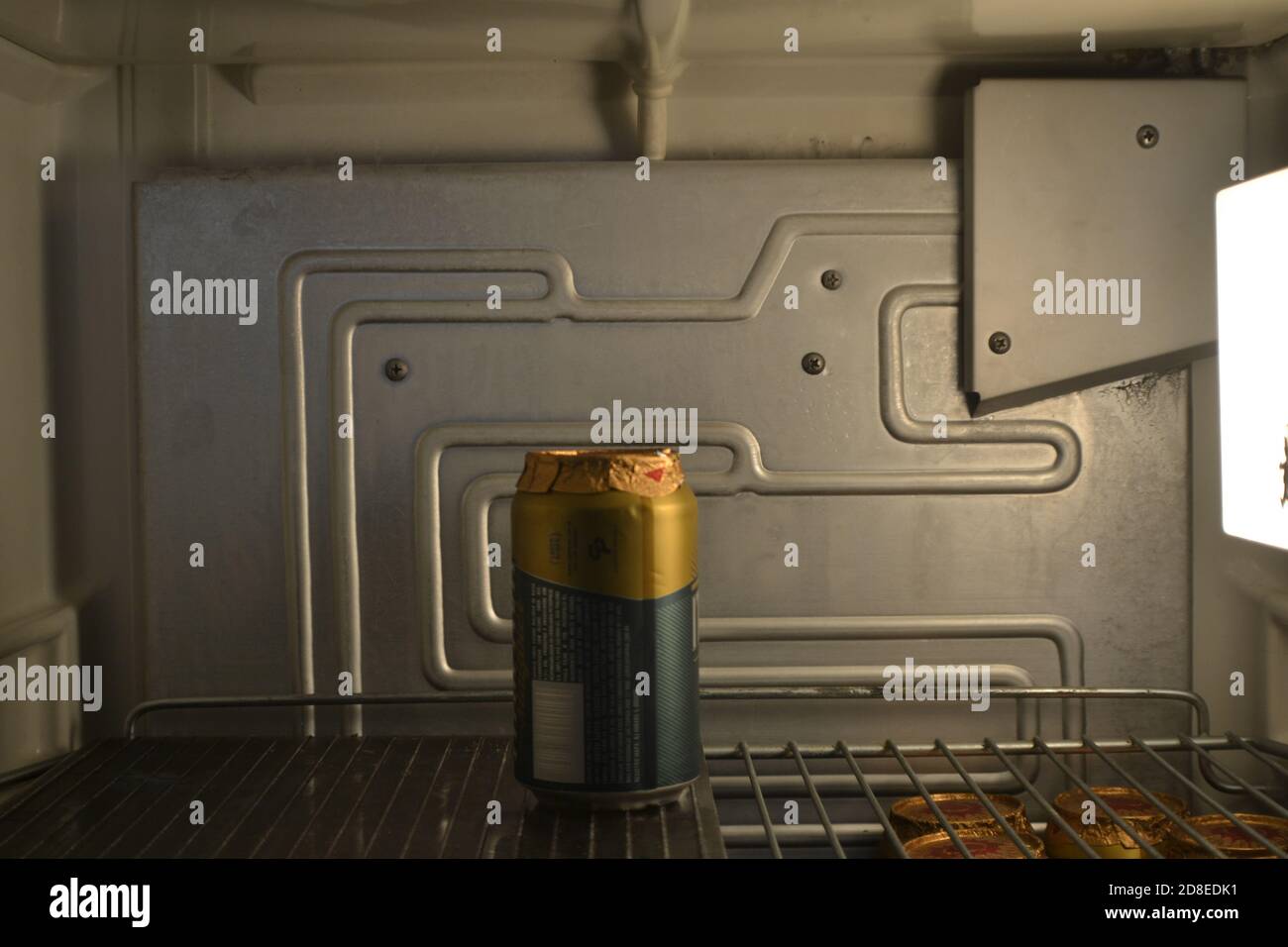 Beer in the refrigerator, open vintage refrigerator showing the inside with internal light and shelf with cold beer can Stock Photo