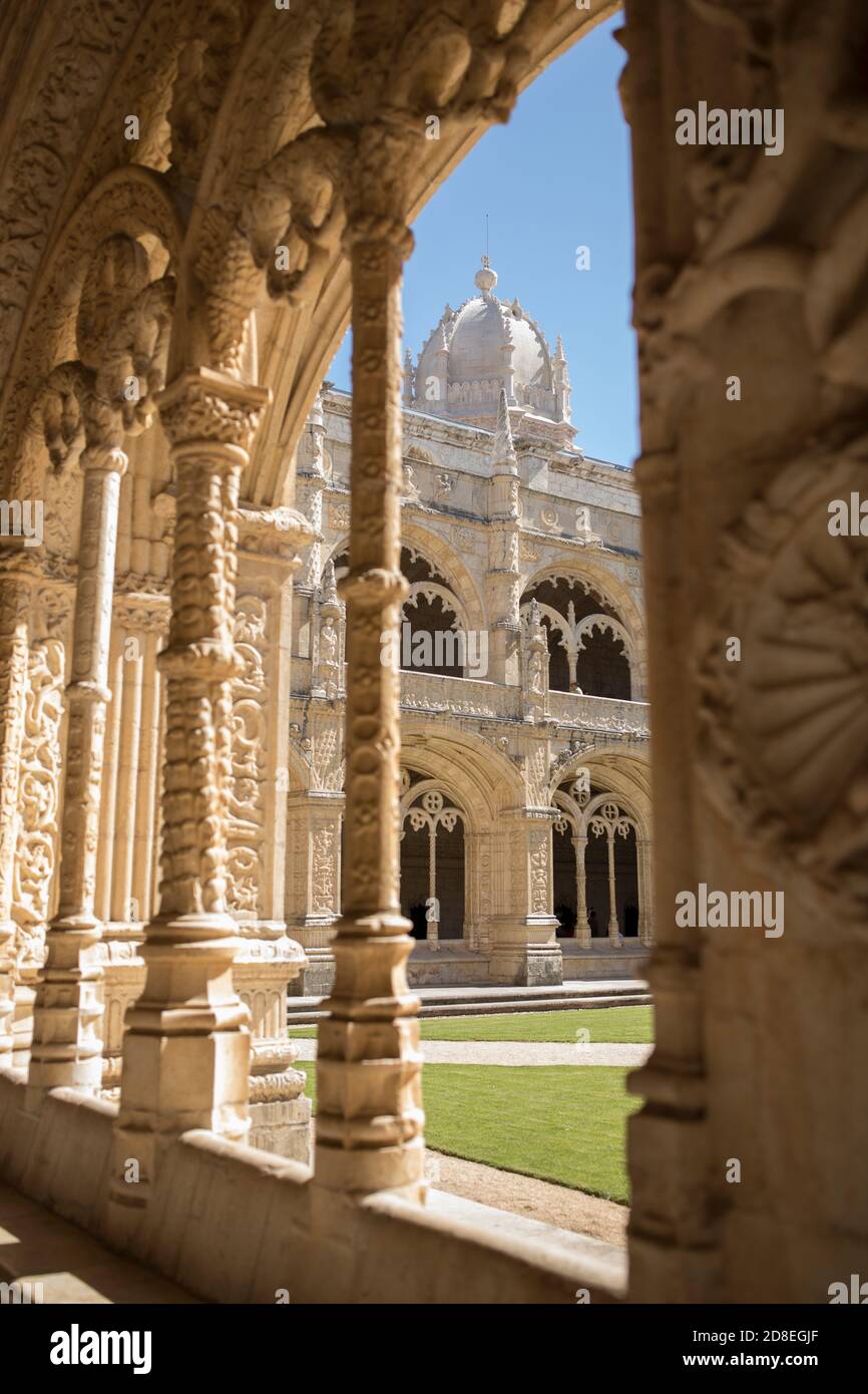 Ornate Manueline architecture and arches with a view of the domed bell tower in the cloister of Jerónimos Monastery in Lisbon, Portugal, Europe. Stock Photo
