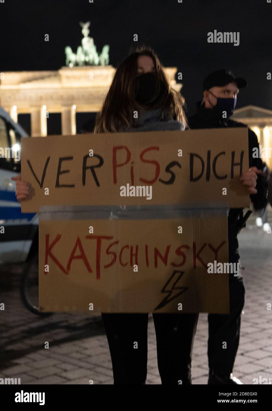Berlin, Germany. 29th Oct, 2020. A woman holds a poster in front of the Brandenburg Gate 'VerPiSs Dich Katschinsky' - an allusion to the leader of the Polish ruling party PiS, Kaczynski. Demonstrators protested here against a tightening of the abortion ban in Poland. Credit: Paul Zinken/dpa-Zentralbild/dpa/Alamy Live News Stock Photo