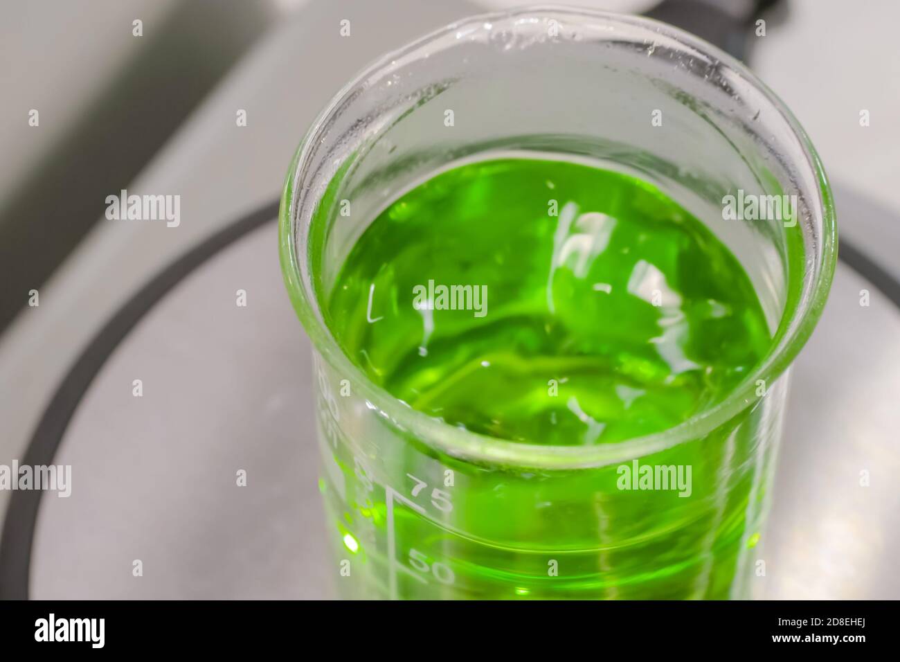 Magnetic mixer stirrer with fast moving stir bar for mixing green liquid at medical lab, exhibition: close up. Chemistry, science, pharmaceutical Stock Photo