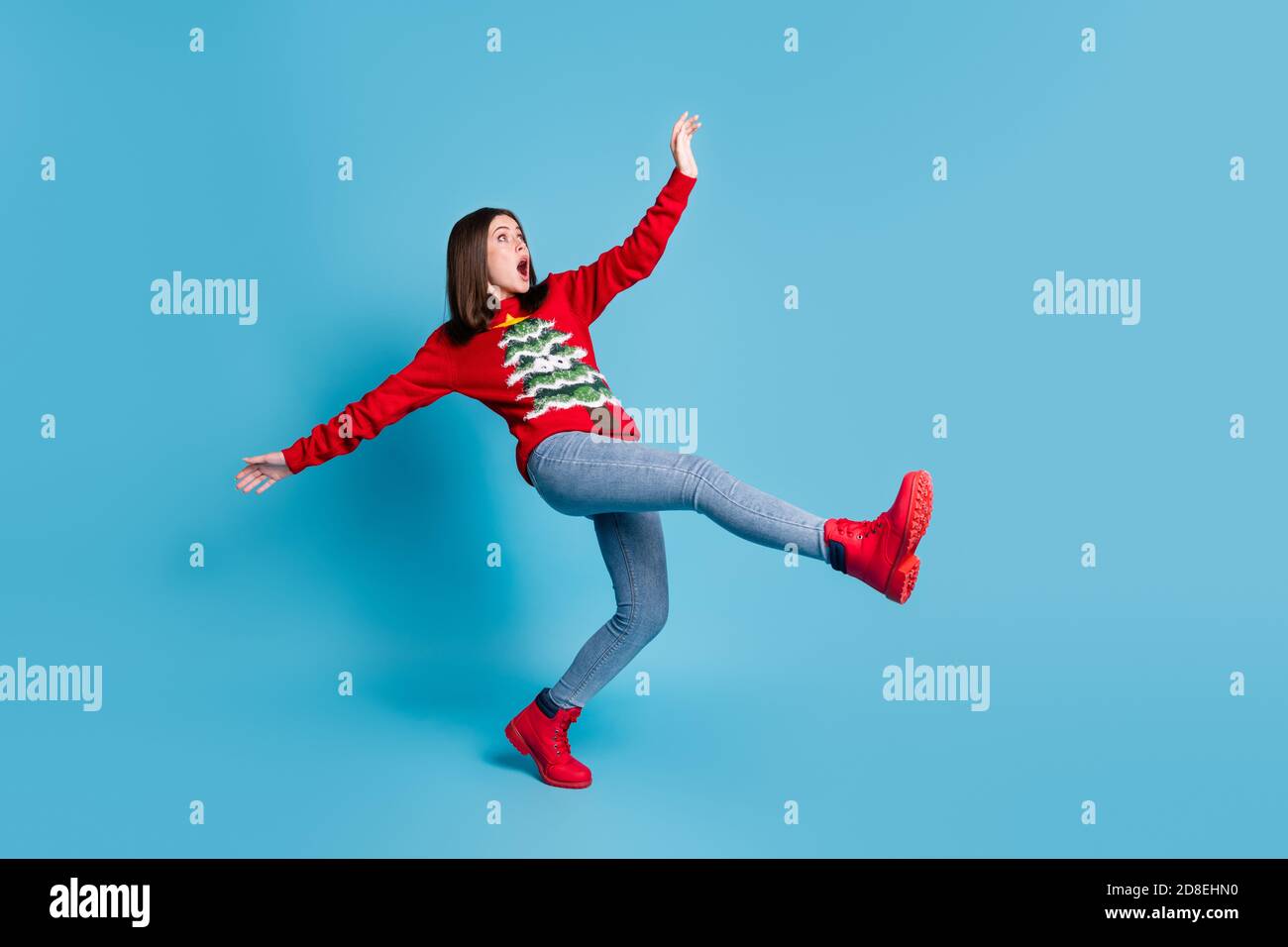 Full body size photo of cute pretty lady stand tiptoe raise hands funny falling open mouth terrified mad look empty space wear red sweater jeans boots Stock Photo