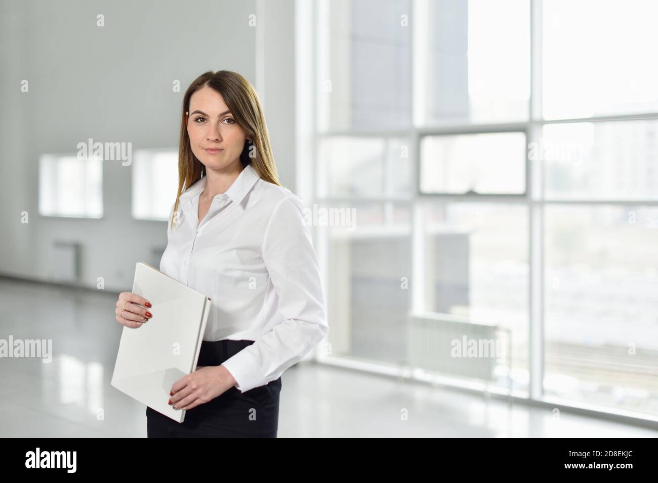 Portrait of a entrepreneur woman with documents in her hands on the background of an empty office for new business Stock Photo
