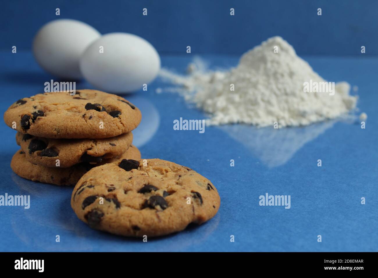 kitchen cooking process homemade chocolate cookies with chocolate drops in the background flour and chicken eggs lie on a blue bright rich mirror back Stock Photo