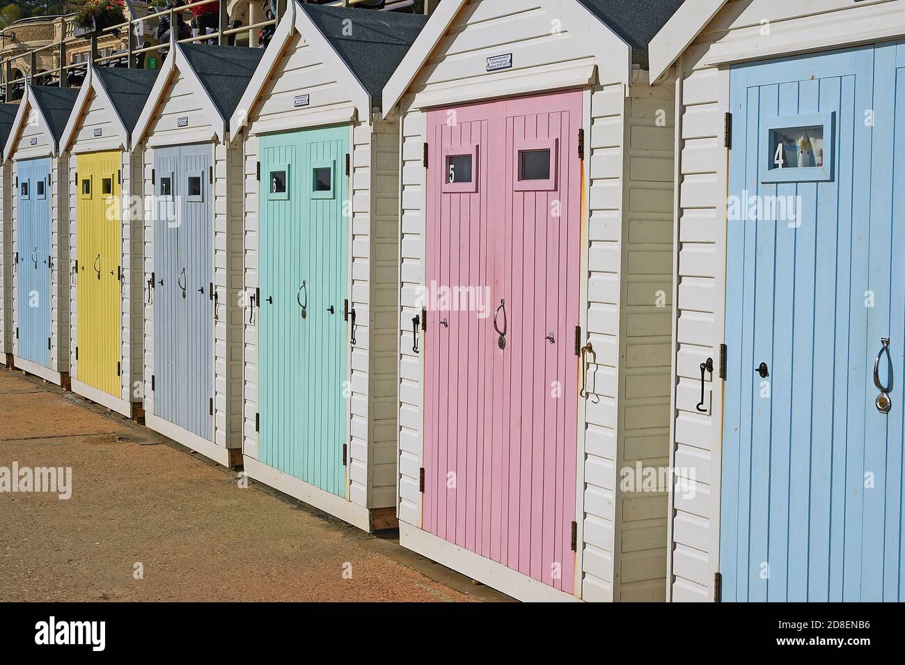 Lyme Regis, Dorset and soft pastel coloured wooden doors adorn beach huts on the seafront promenade. Stock Photo