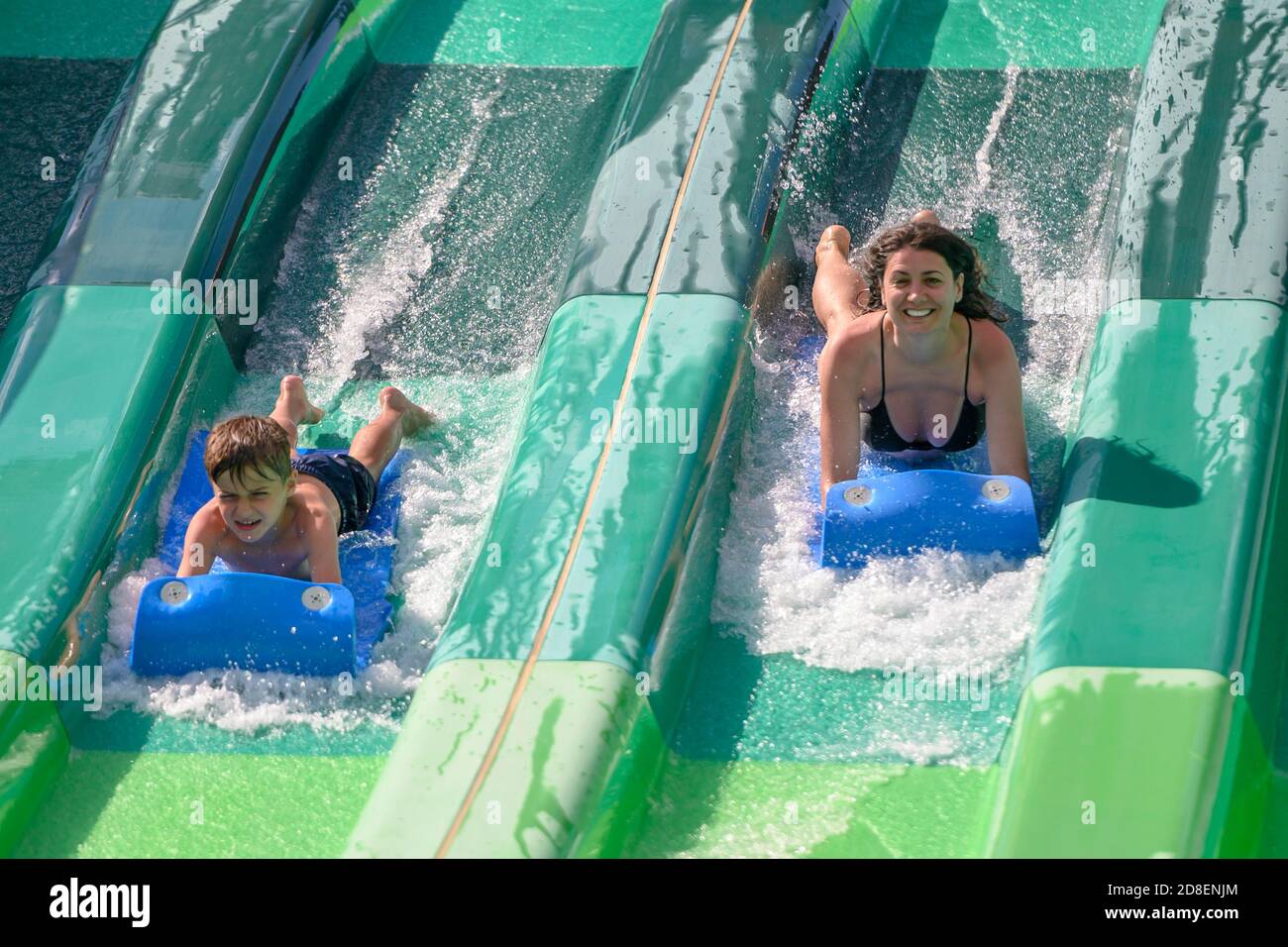 Young woman and her child enjoying extreme fall on water slide, in a