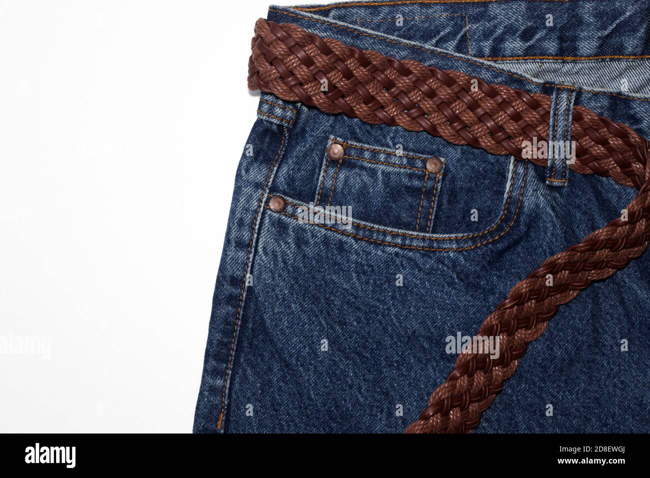 Classic jeans with five pockets close-up. jeans with a woven belt of brown leather and coarse thick threads. vintage blue textured denim fabric on pure white background. Fashionable casual style Stock Photo