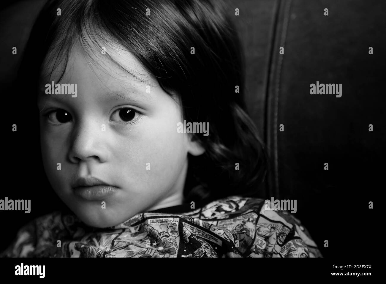 A young boy poses sitting back on a sofa, at home in South Wales in 2016.  ©PRWPhotography Stock Photo