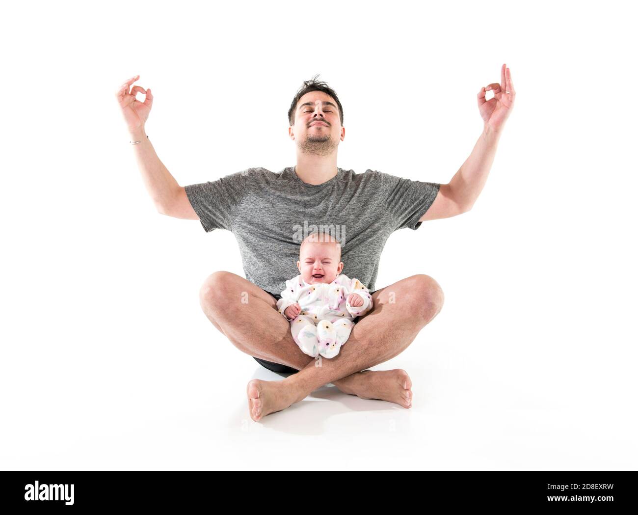 A father does gymnastics yoga with her crying baby Stock Photo