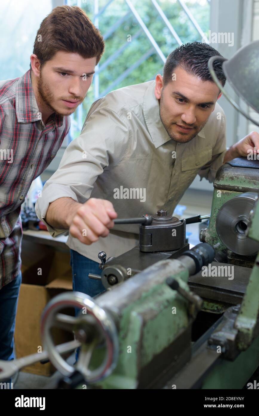 engineer teaching apprentices to use metal processing machines Stock Photo