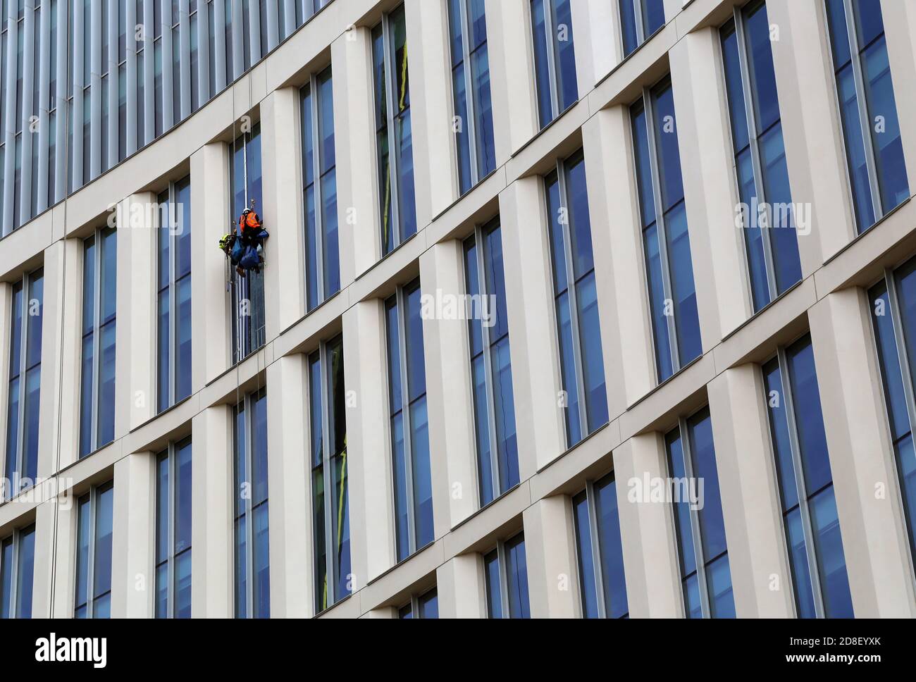 Window washer. Low Angle View of Worker Cleaning Modern Office Building. Manchester, UK. Stock Photo