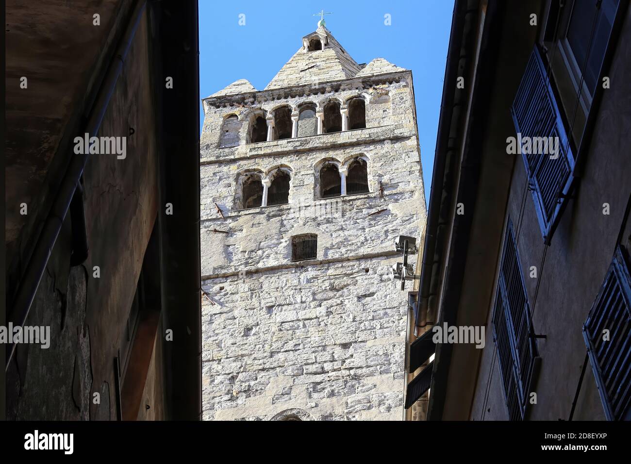 Glimpse from a narrow street in the historic center of Genoa of the Gothic bell tower of the San Giovanni di Pre church against a blue clear sky. Stock Photo