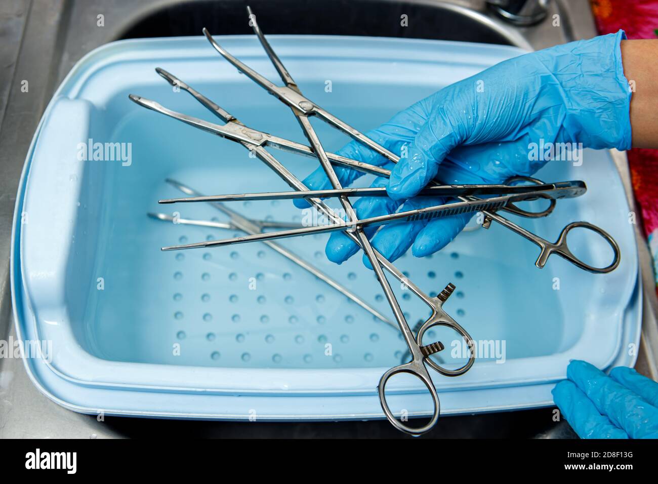 A medical worker rinses surgical instruments in a tray of water