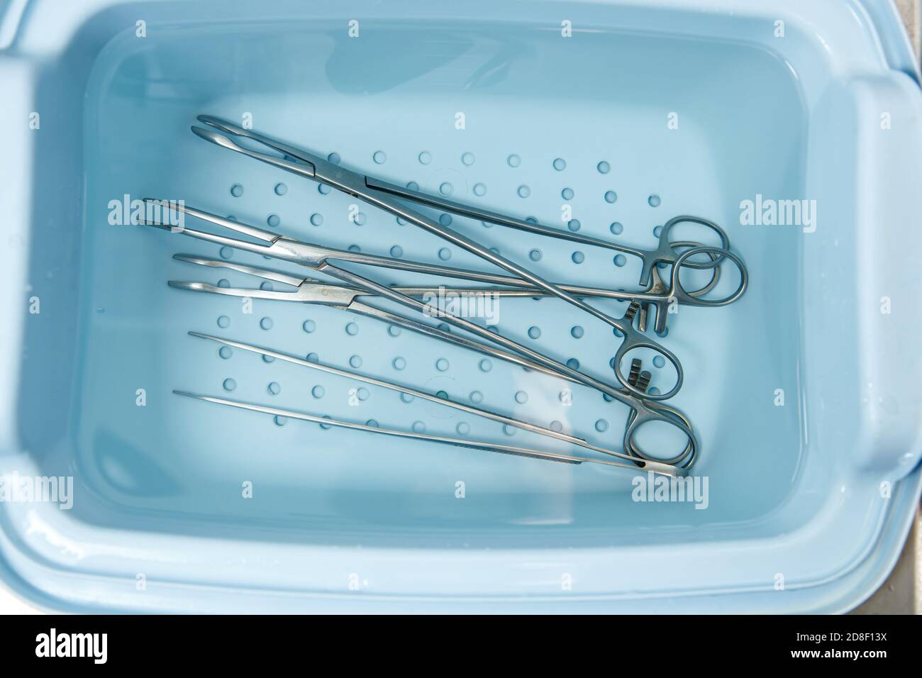 Surgical instruments are rinsed in a tray with water. Disinfection of