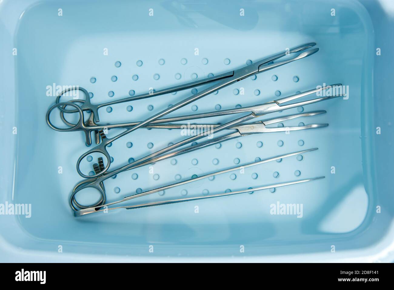 Surgical instruments are rinsed in a tray with water. Disinfection of