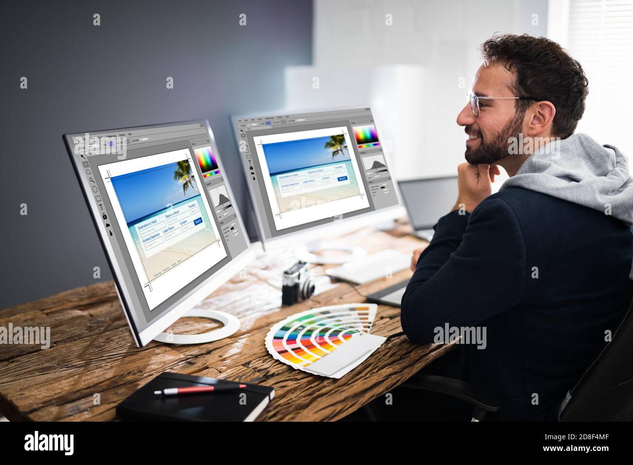 Designer Editing Photos On Multiple Computer Screens Stock Photo