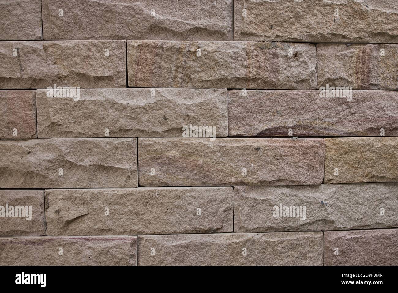 This unique photo shows the structure of a sandstone wall that stands outdoors. the individual stone slabs are very clearly visible with their pattern Stock Photo