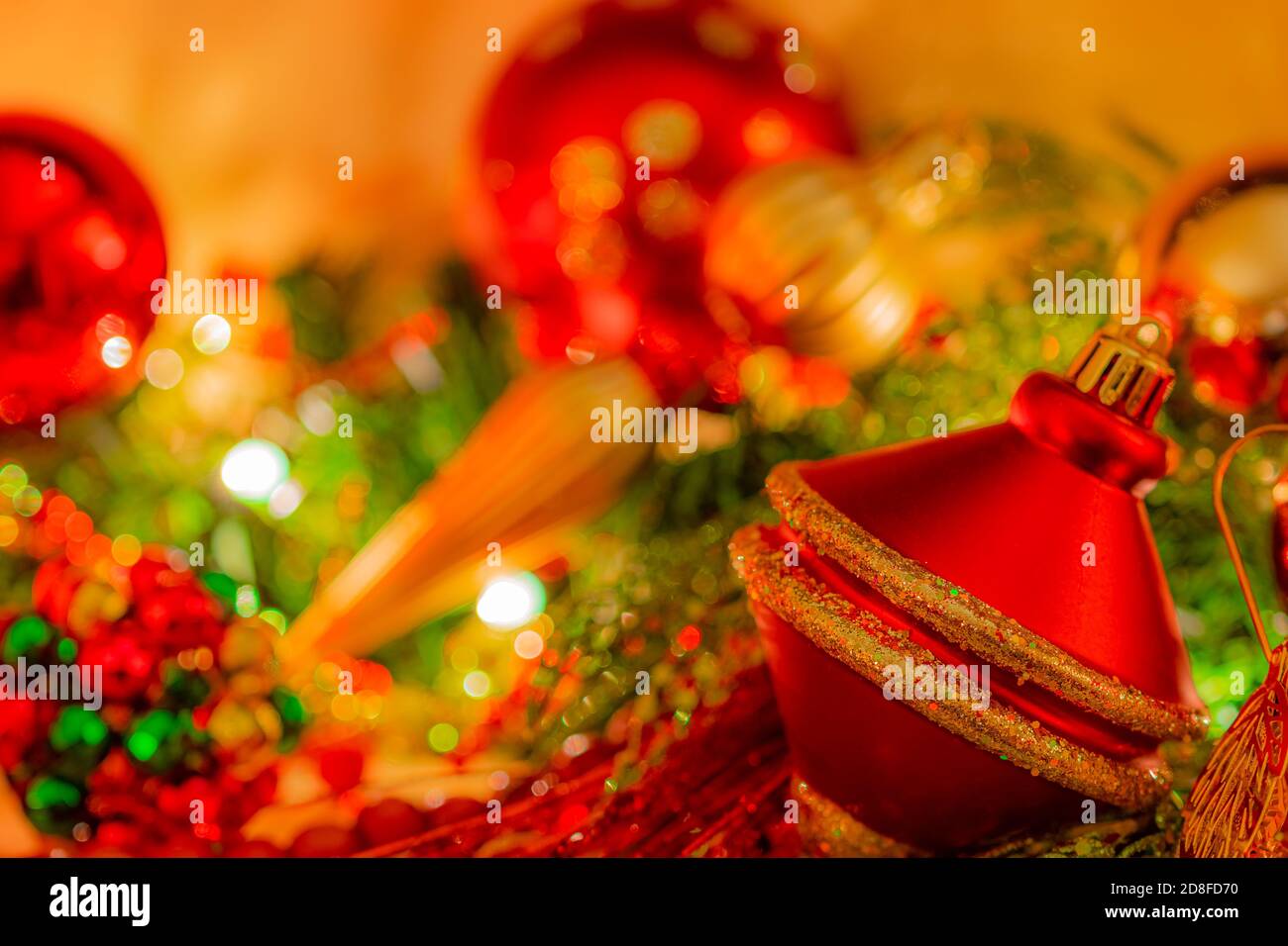 Christmas ornament in red and gold color is  surrounded by soft focus ornaments in bright glittering  colors on a fireplace mantel. Stock Photo