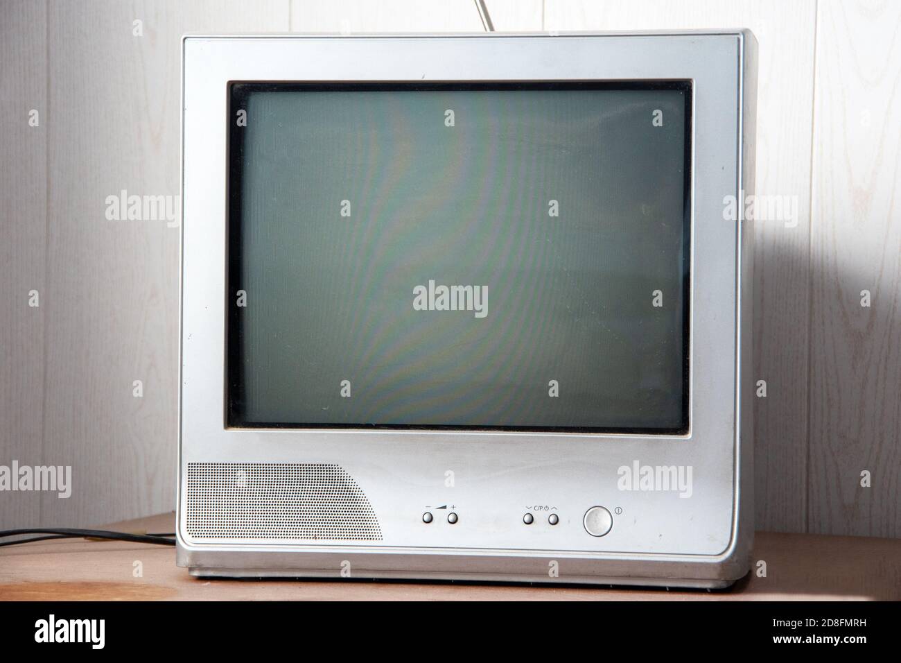 An old tube television with antennas stands on a dusty table. Front