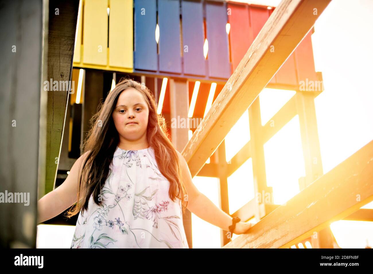 A portrait of trisomie 21 adult girl outside at sunset having fun on a park Stock Photo