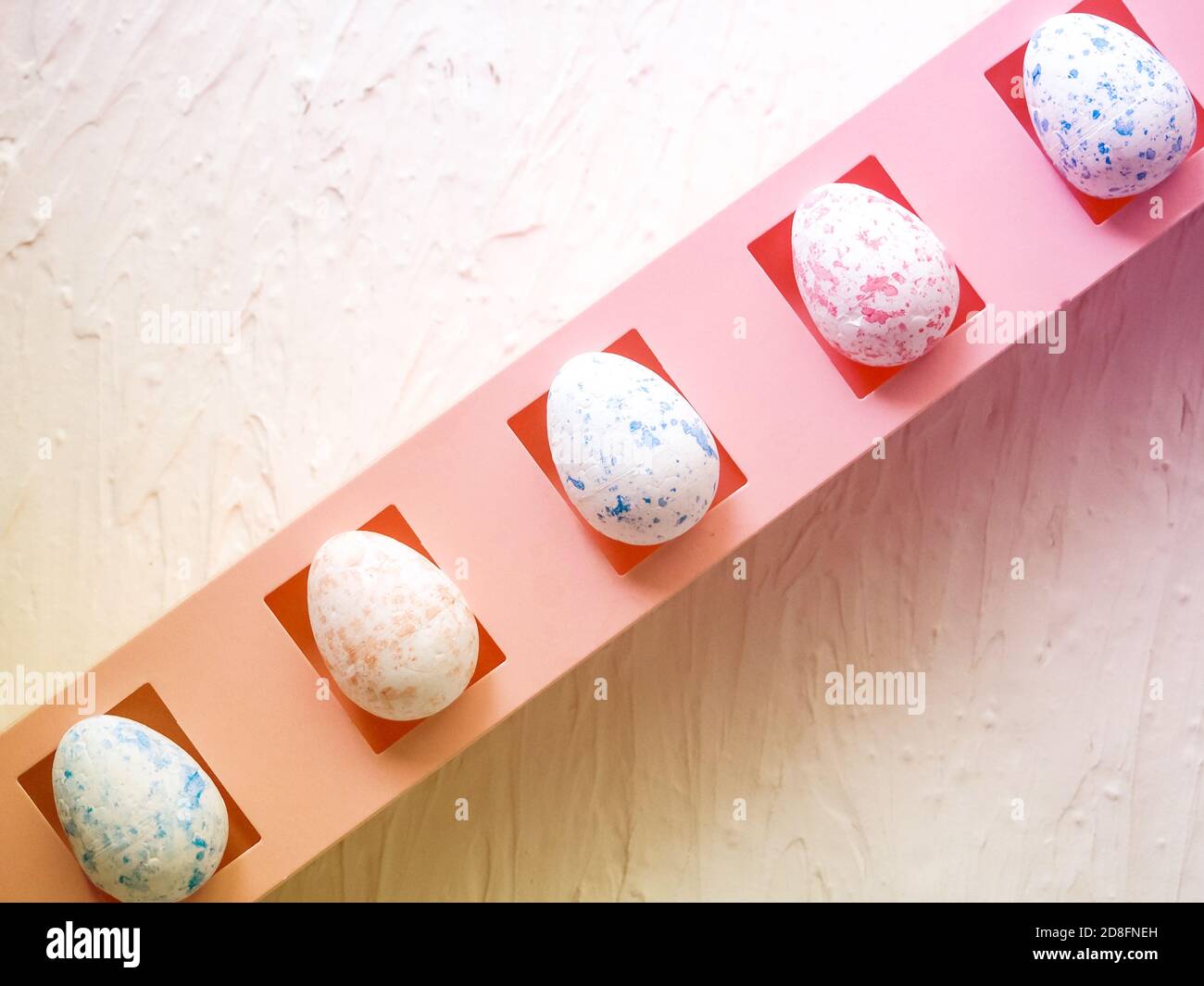 easter, holidays and tradition concept - row of colored artificial eggs on pink. Stock Photo