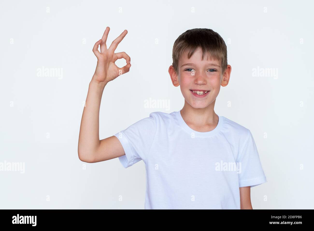 Portrait of cute Caucasian boy showing ok gesture, success, agreement on white background. Successful study concept Stock Photo