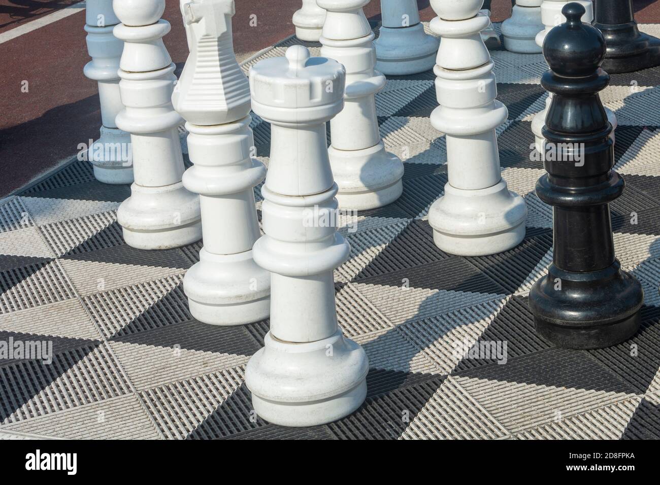 Big street chess on giant chessboard in park outside. large plastic chess pieces. Selective focus. Stock Photo
