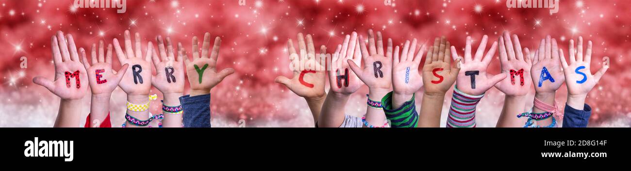 Children Hands Building Word Merry Christmas, Red Christmas Background Stock Photo