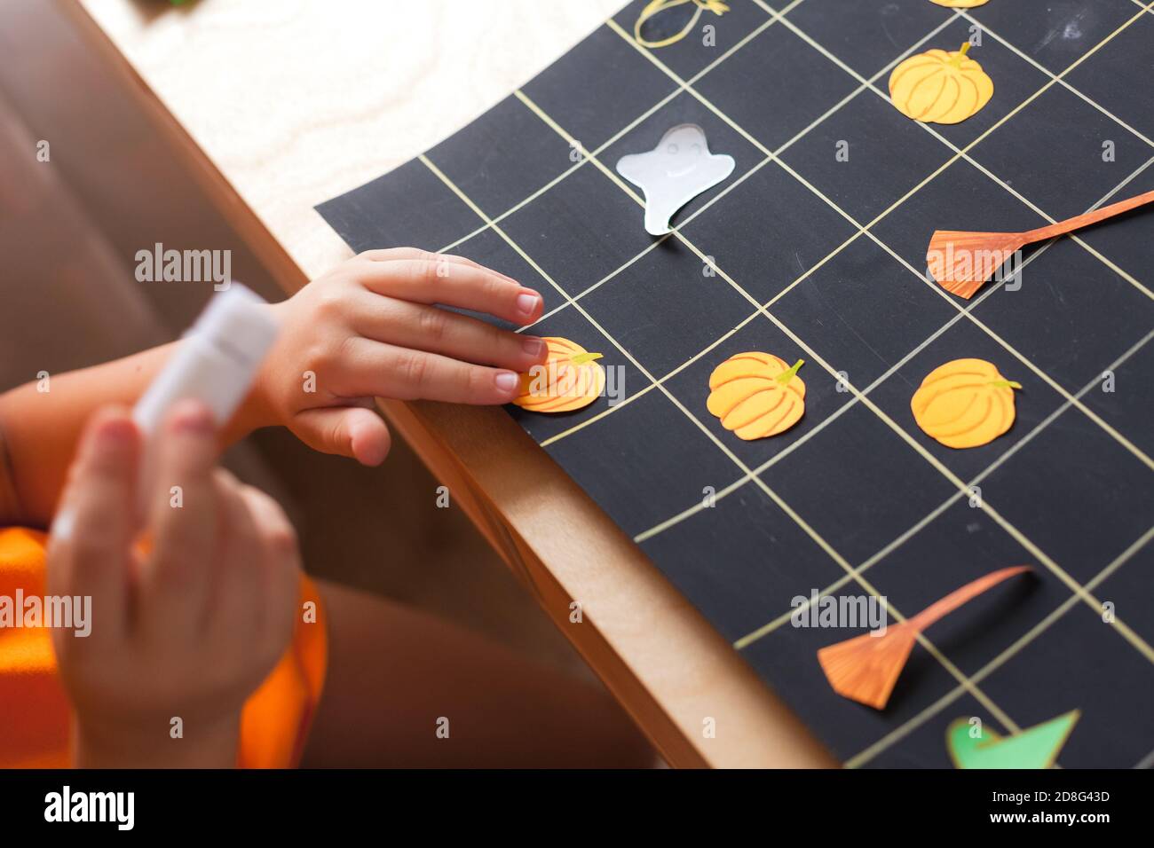 Preschooler boy making board game field for Halloween game, child