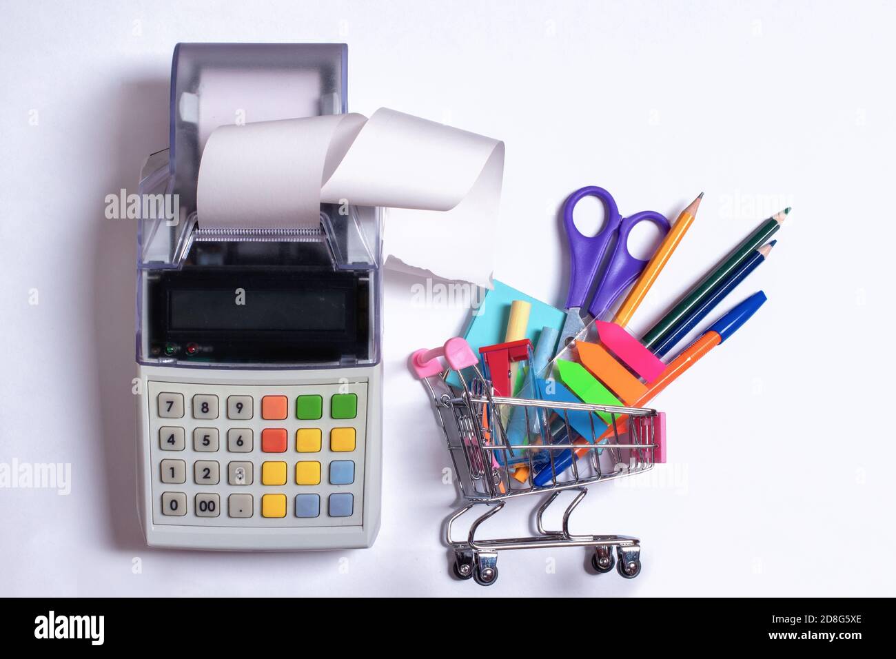 Top view photo of a shopping trolley with colorful stationery and a cash register with a receipt tape Stock Photo