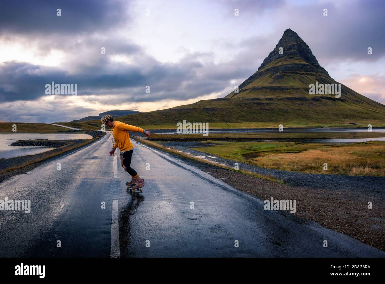 Action shot of a skater on a wet road around mount Kirkjufell in Iceland Stock Photo