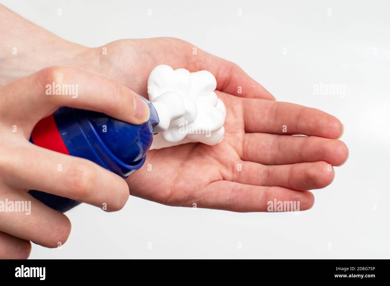 A close-up of a female hand squeezing foam in the palm of a hand from a blue balloon. Place soap foam with foam on hand Stock Photo
