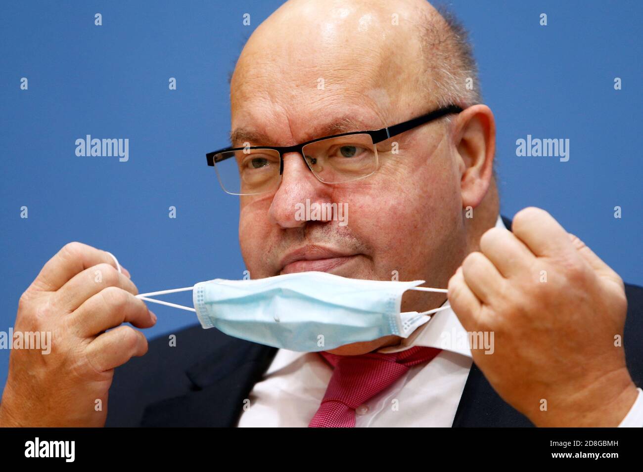 30 October 2020, Berlin: Peter Altmaier (CDU), Federal Minister of Economics and Energy, takes off his mouth guard at a press conference to present the federal government's autumn economic forecast. The corona crisis had caused an economic slump, especially in spring. Photo: Michele Tantussi/Reuters-Pool/dpa Stock Photo