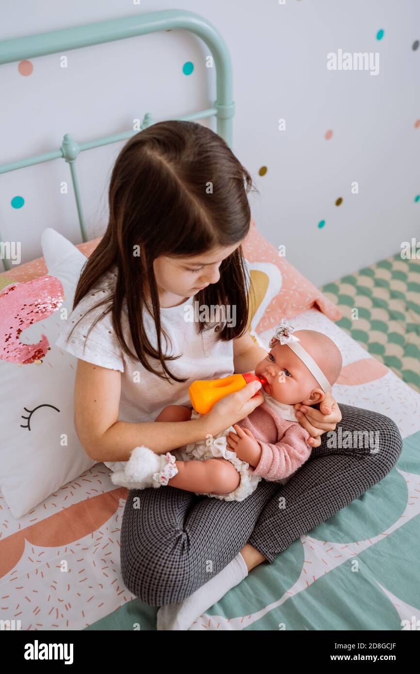 little girl playing feeding her baby doll Stock Photo