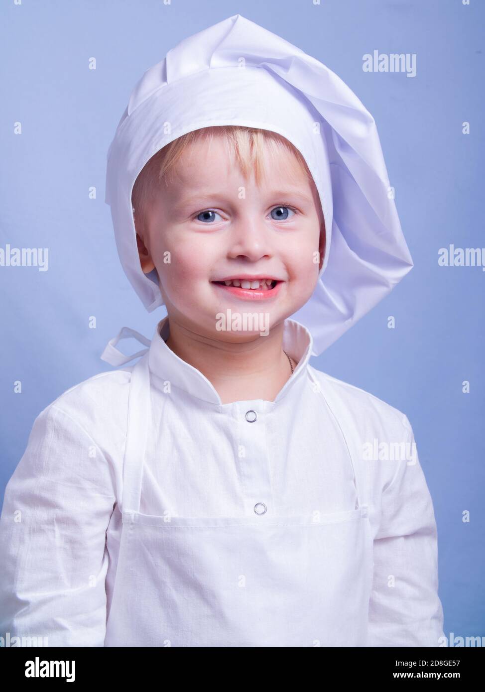 a 3yearold boy in a suit and a chef's cap smiles at the camera