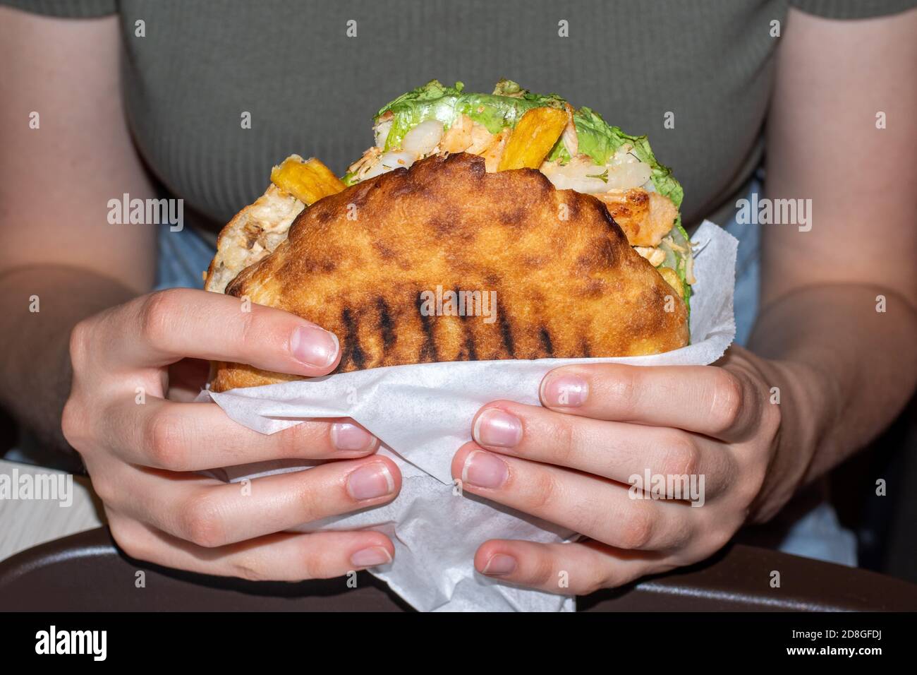 Close-up of female hands holding a large hamburger, front view. Unhealthy food concept. Overweight concept Stock Photo