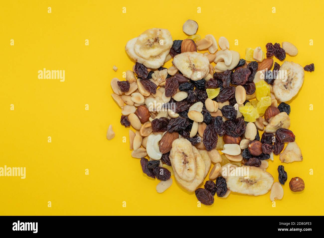 Closeup mix nuts and dry fruits on a yellow background, copy space