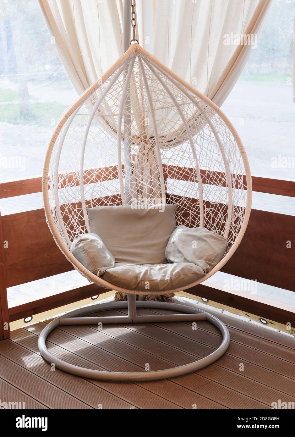 Wicker rattan hanging chair nest on a terrace of a house. cosy place to rest and relax. modern interiors. Stock Photo