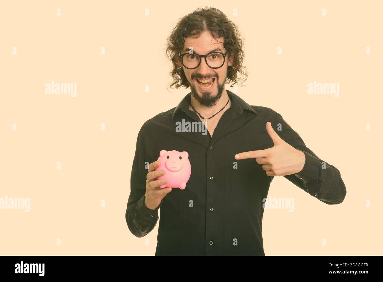 Happy handsome Caucasian man holding piggy bank and pointing finger ...