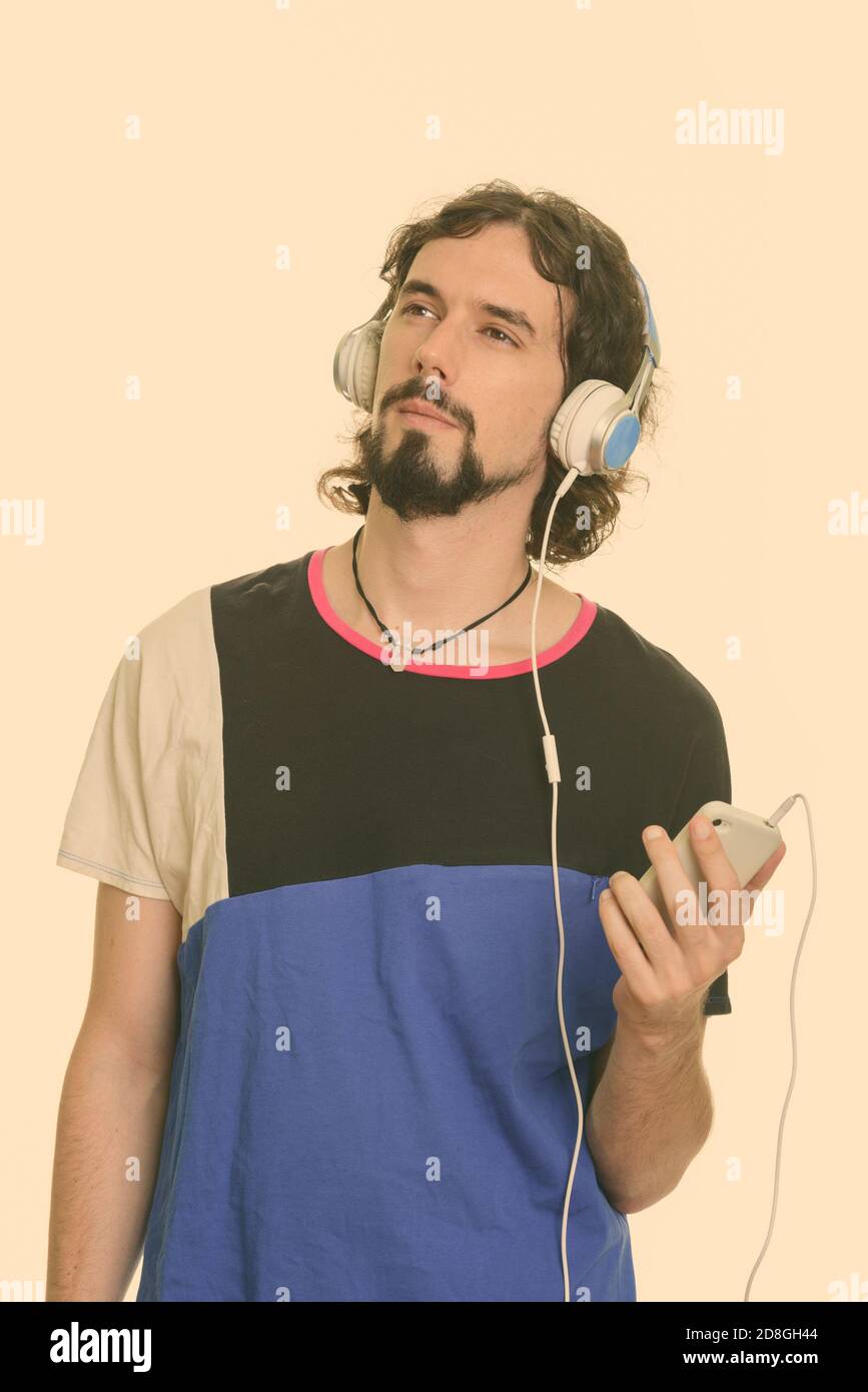Handsome Caucasian man holding mobile phone and listening to music while thinking Stock Photo