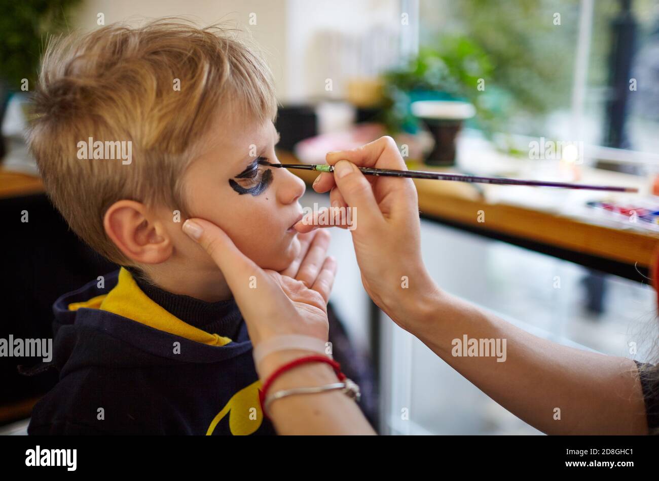 Happy family preparing for Halloween! Mother and son getting ready for Halloween party, traditional Mexican carnival, Santa Muerte make make-up Stock Photo