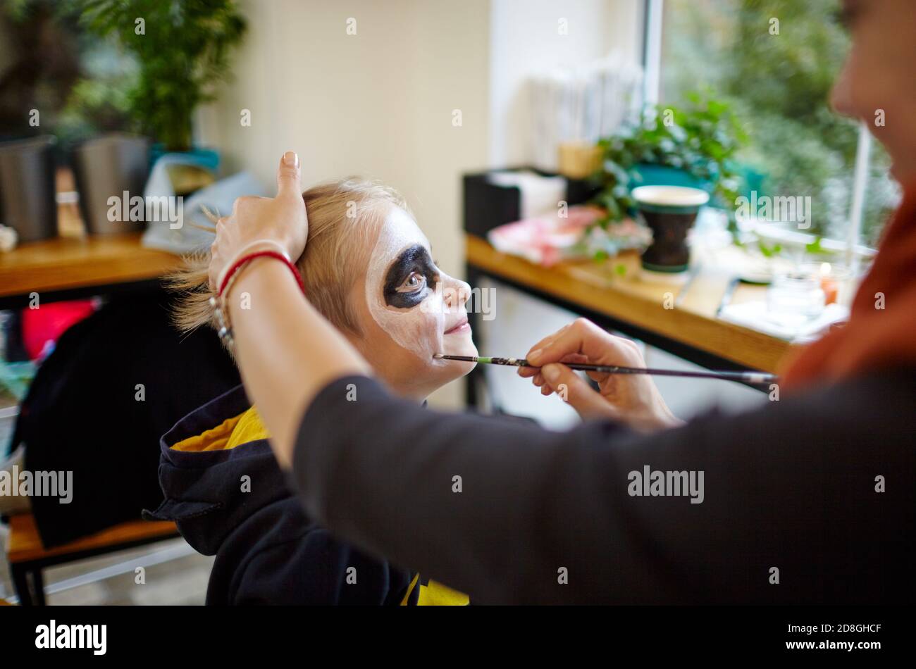 Happy family preparing for Halloween! Mother and son getting ready for Halloween party, traditional Mexican carnival, Santa Muerte make make-up Stock Photo