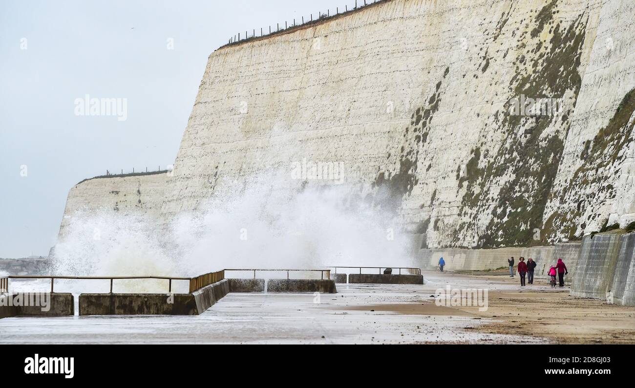 Brighton UK 30th October 2020 - Walkers pass by waves crashing over the undercliff walk at Saltdean near Brighton this morning . Warnings have been issued that stormy weather is forecast for many parts of the UK this coming weekend : Credit Simon Dack / Alamy Live News Stock Photo