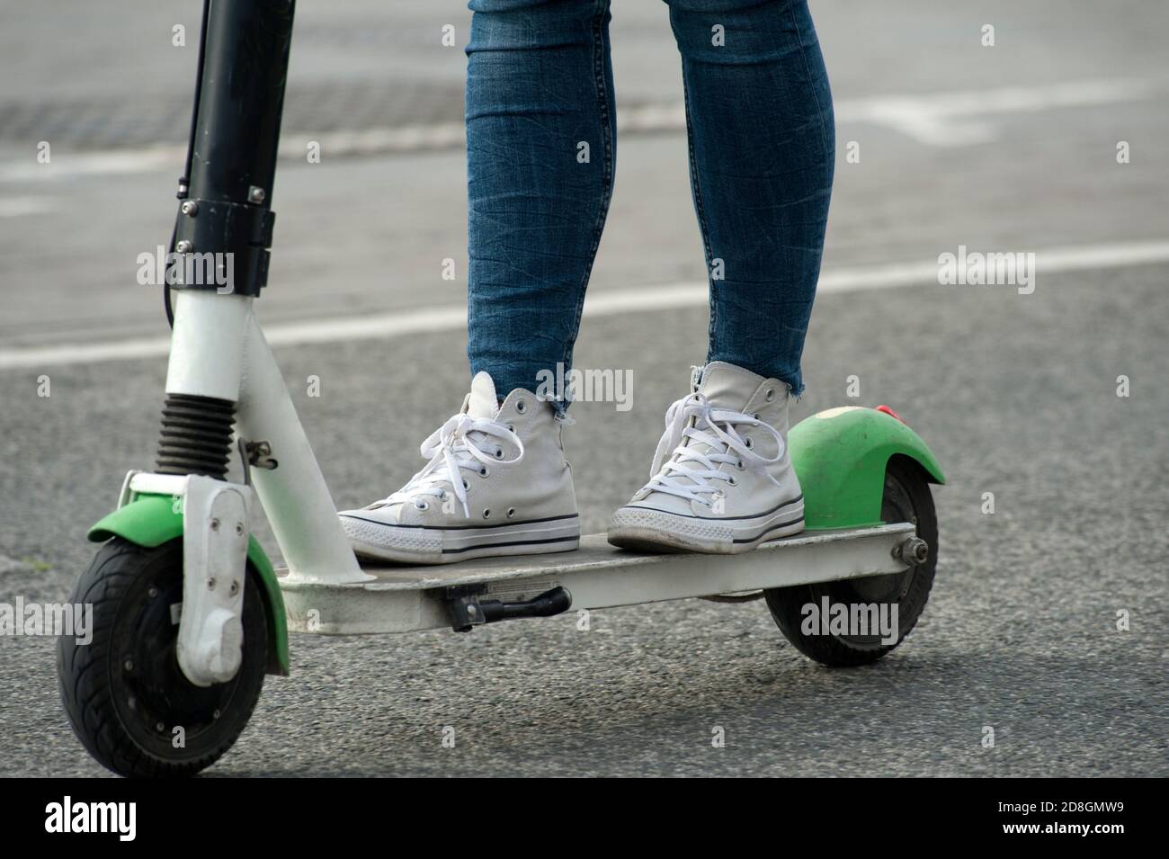 electric scooter in asphalt blue jeans and white casual shoes Stock Photo -  Alamy