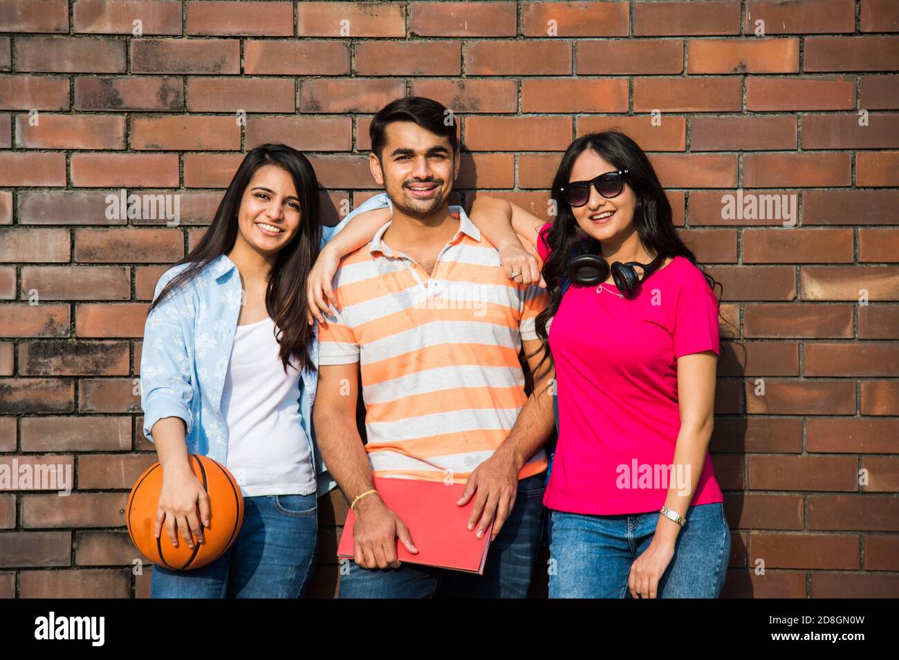 Cheerful Indian asian young group of college students or friends laughing together while sitting, standing or walking in campus Stock Photo