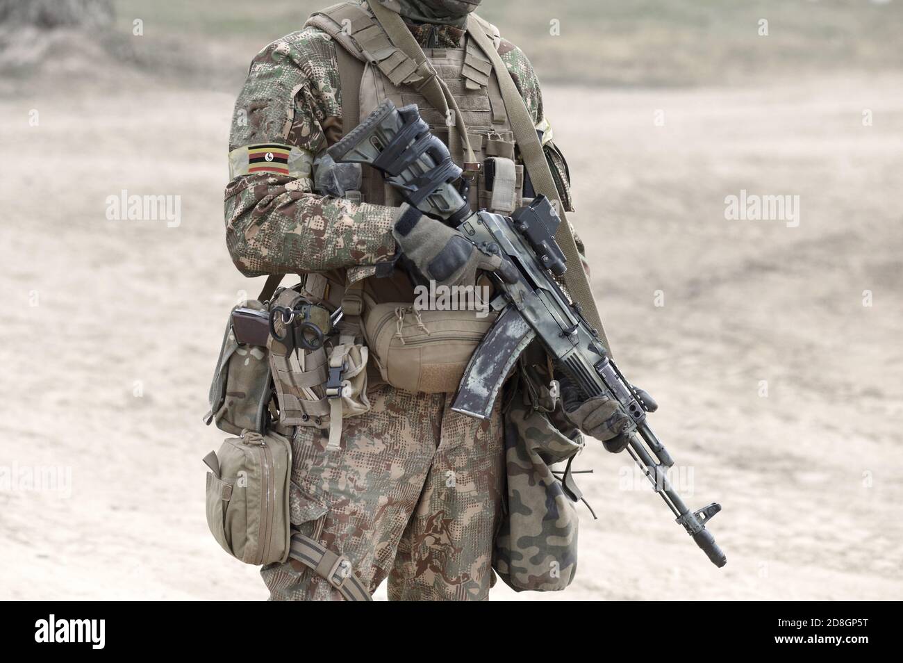 Soldier with assault rifle and flag of Uganda on military uniform