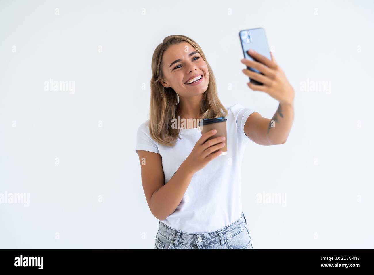 Young beautiful woman using smartphone selfie time, holding coffee cup ...