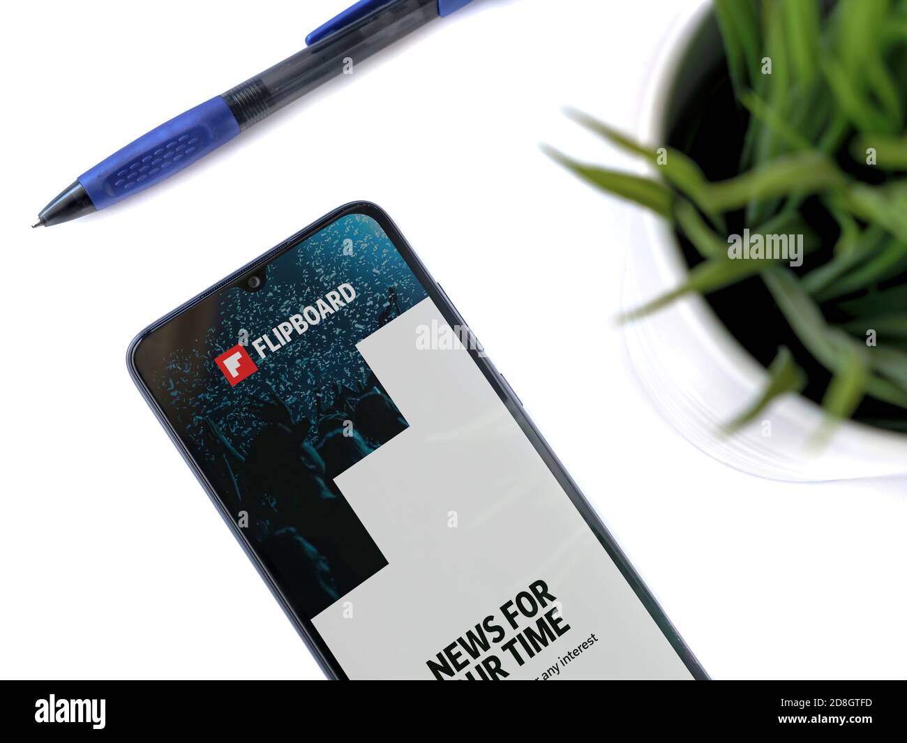 Lod, Israel - July 8, 2020: Modern minimalist office workspace with black mobile smartphone with Flipboard app launch screen with logo on white backgr Stock Photo