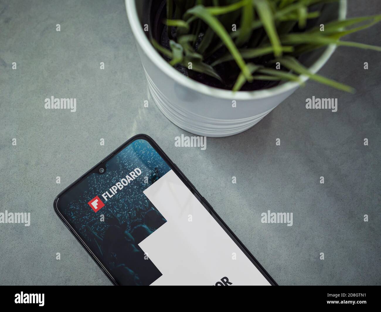 Lod, Israel - July 8, 2020: Modern minimalist office workspace with black mobile smartphone with Flipboard app launch screen with logo on marble backg Stock Photo