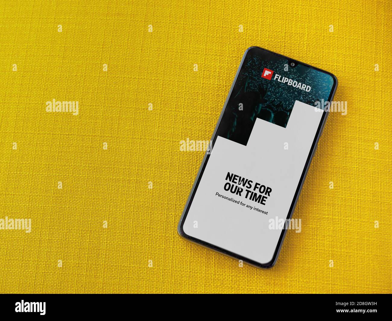 Lod, Israel - July 8, 2020: Flipboard app launch screen with logo on the display of a black mobile smartphone on a yellow fabric background. Top view Stock Photo